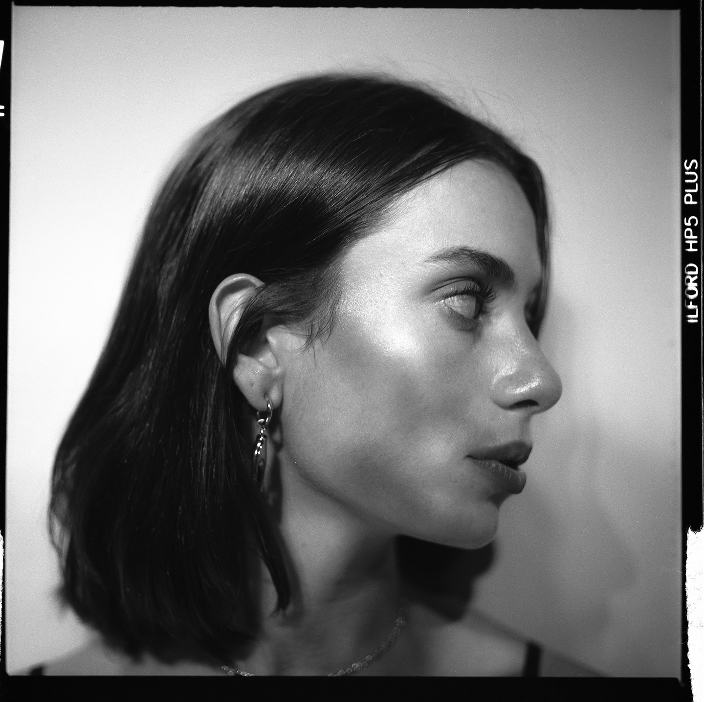 A woman with dark hair and an earring looks to the right in a black and white portrait.
