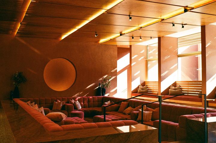 Sunlight streams into a lounge area with red couches and a circular wall decoration.