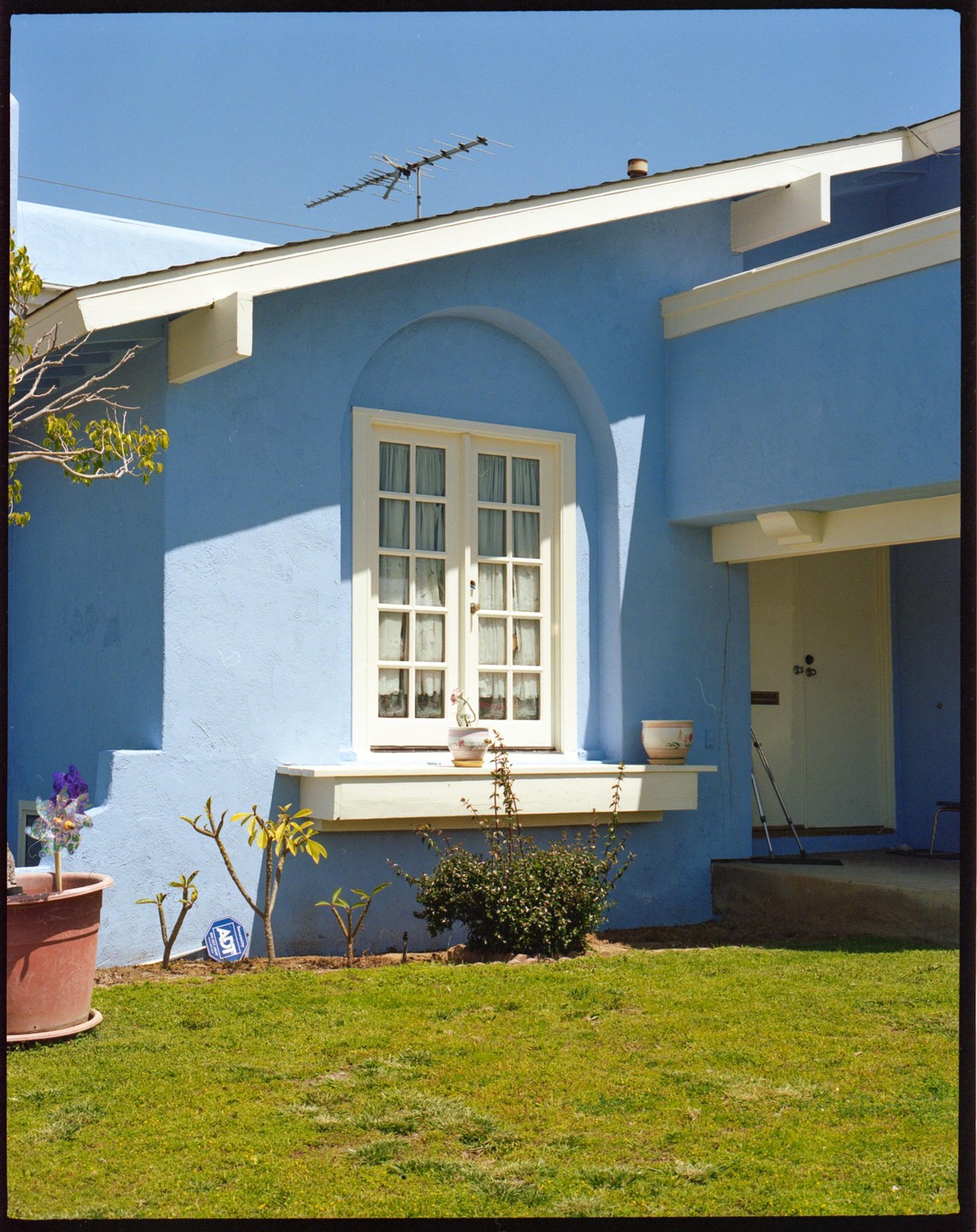 A light blue house with a white window and a green lawn in front.