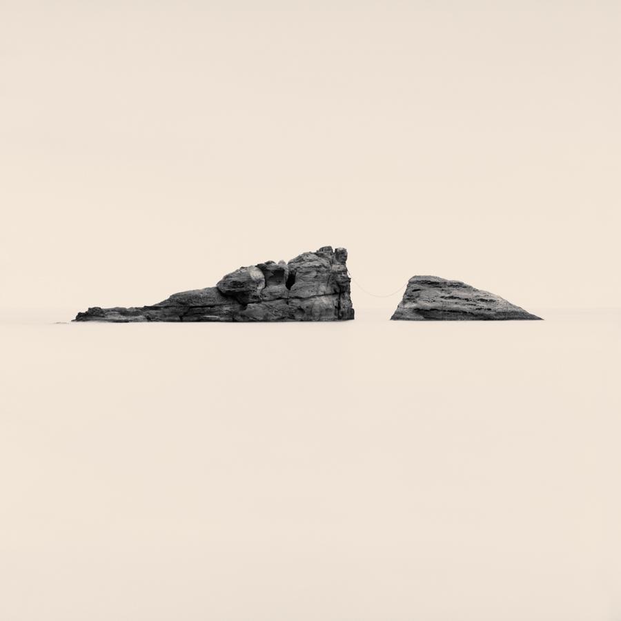 Two rock formations are visible in a body of water, connected by a thin line.