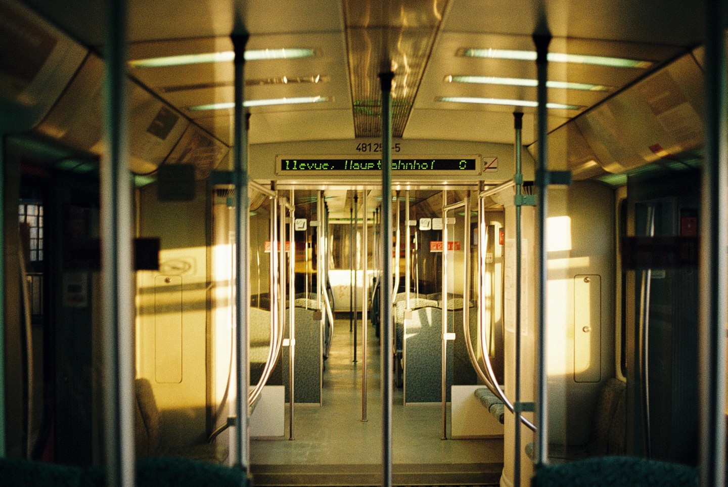 The interior of an empty train car is illuminated by golden light.