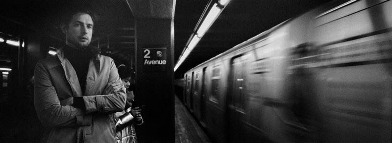 A man stands on a subway platform as a train speeds by.