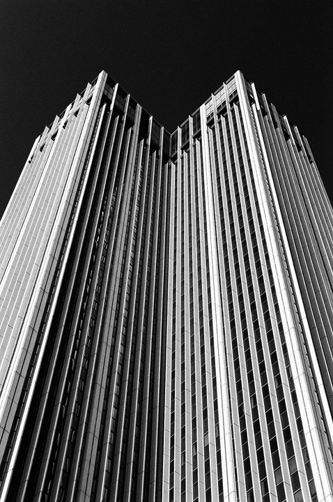 A tall, modern building with many vertical lines is photographed from a low angle against a dark sky.