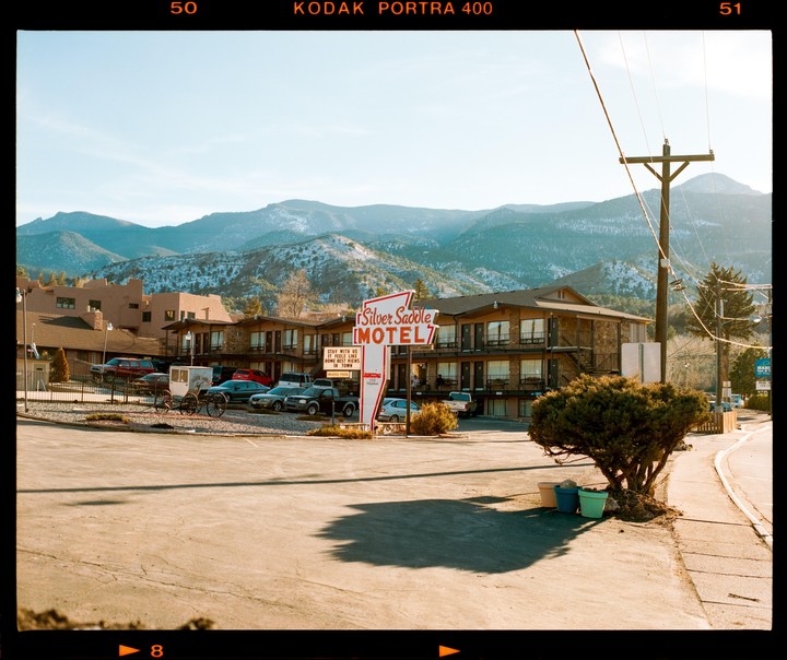 A motel sign stands in front of a building with mountains in the background.