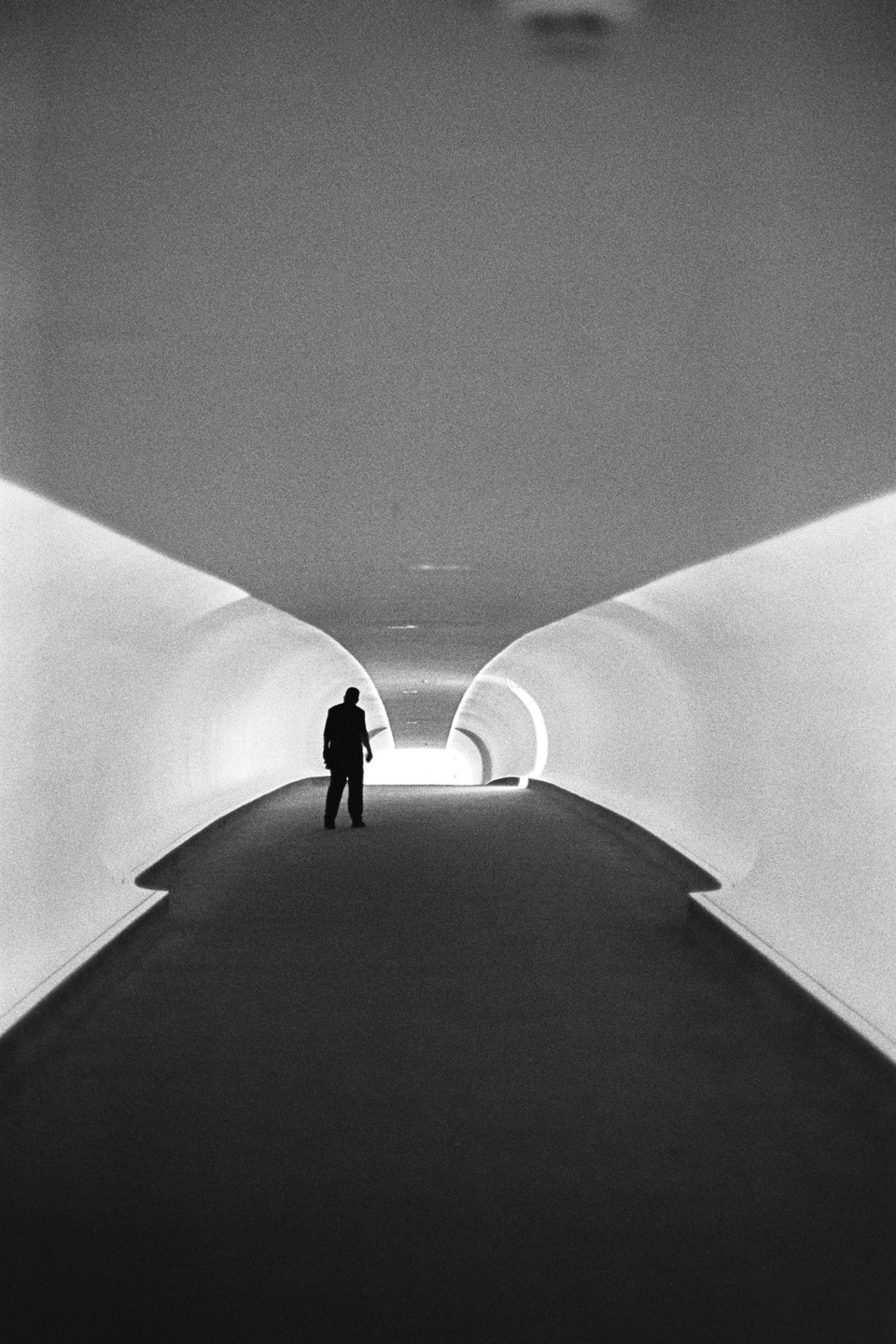 A man stands in a brightly lit, modern tunnel.