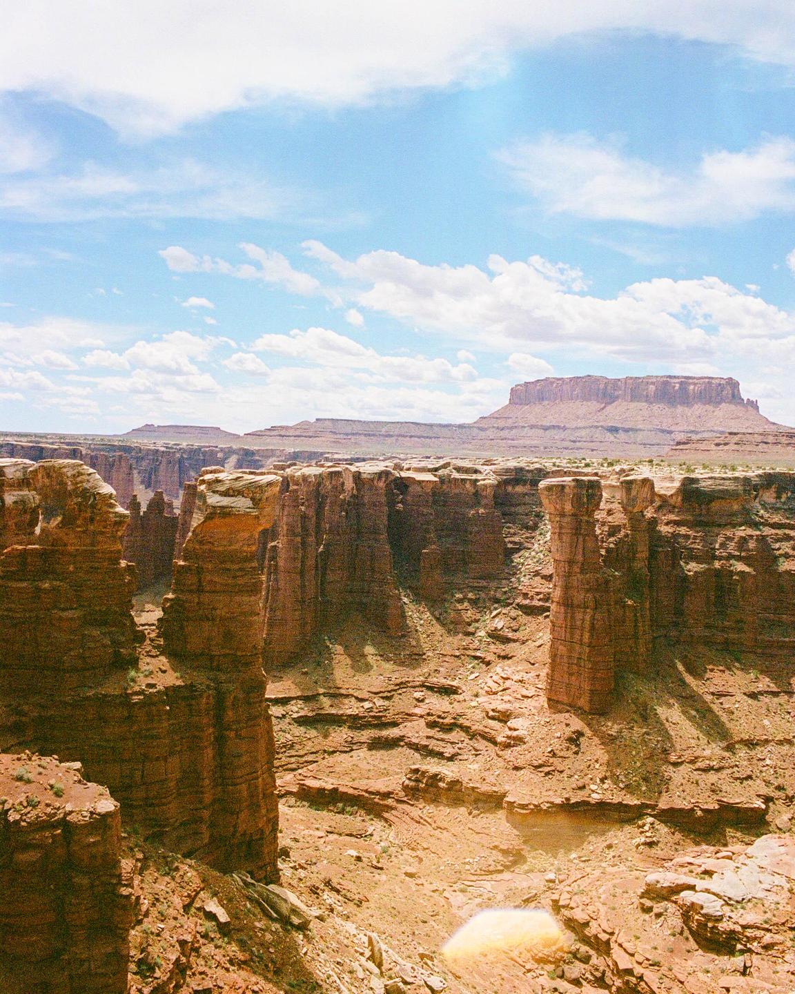 A vast canyon with towering rock formations under a partly cloudy sky.