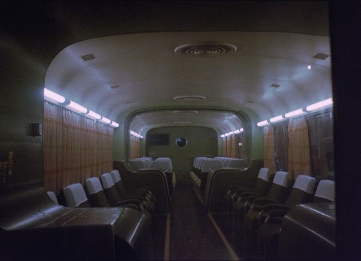 The interior of a subway car is visible, with rows of seats and fluorescent lights illuminating the space.