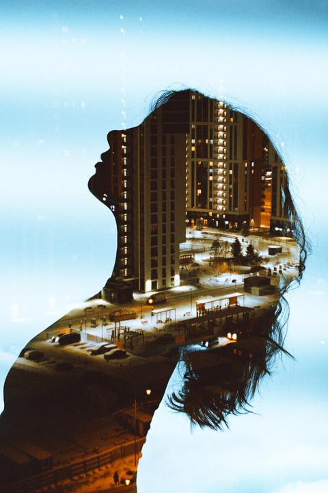 A double exposure shows the silhouette of a woman's head overlaid with a night scene of city buildings and streets.