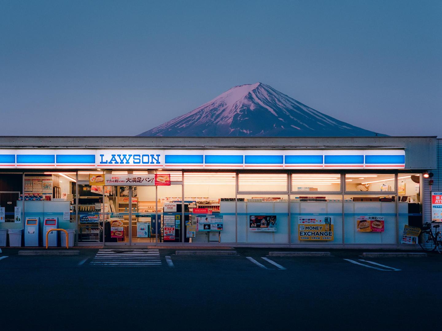 A Lawson convenience store with Mount Fuji in the background at dusk.