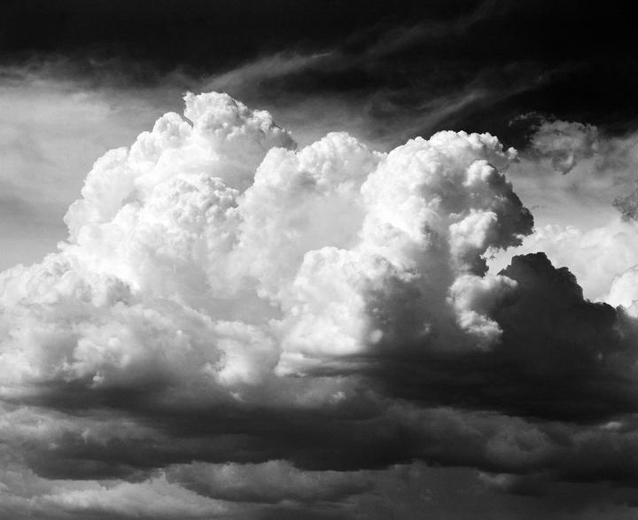 A large, bright cumulus cloud dominates the sky, surrounded by darker clouds.