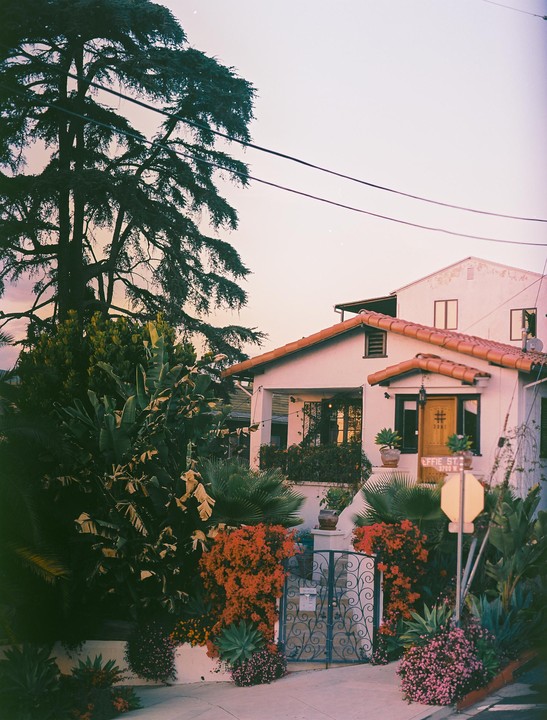 A house with a red tile roof and lush landscaping is visible at dusk.