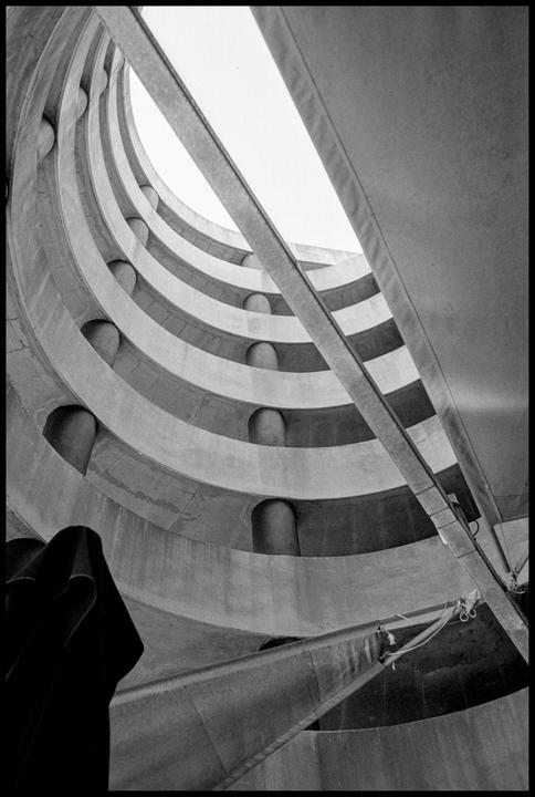 A low-angle view shows the curving concrete ramps of a spiral parking garage.