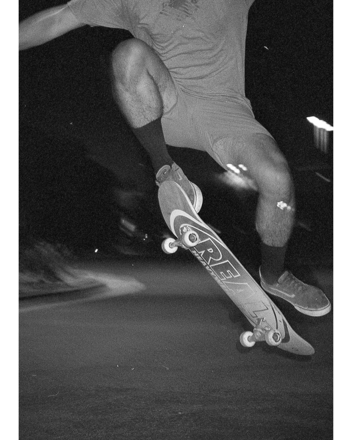 A person is skateboarding at night, captured in a black and white photograph.