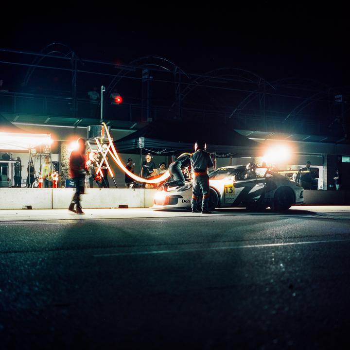 A race car is serviced by a pit crew at night.