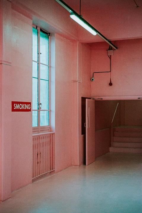 A pink room with a window, a red "SMOKING" sign, and an open doorway leading to stairs.