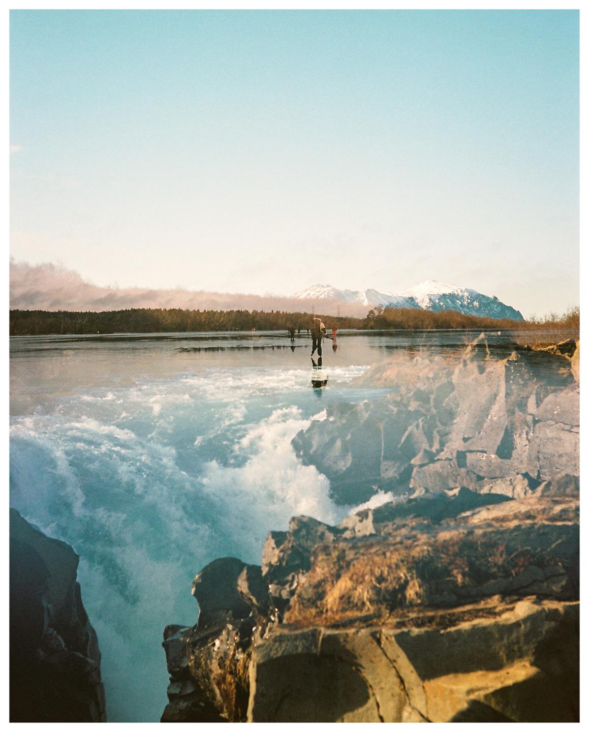 A double exposure shows a person ice skating on a frozen lake with mountains in the background, superimposed over a waterfall and rocks.