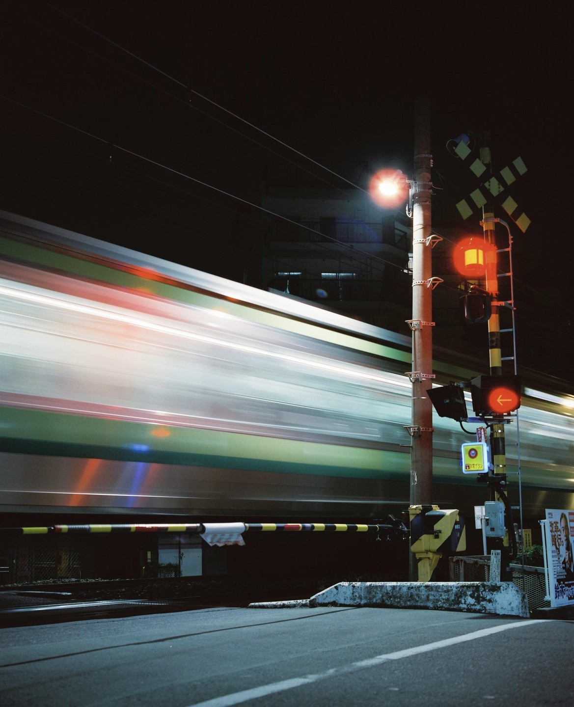 A train blurs past a railroad crossing at night in Tokyo.