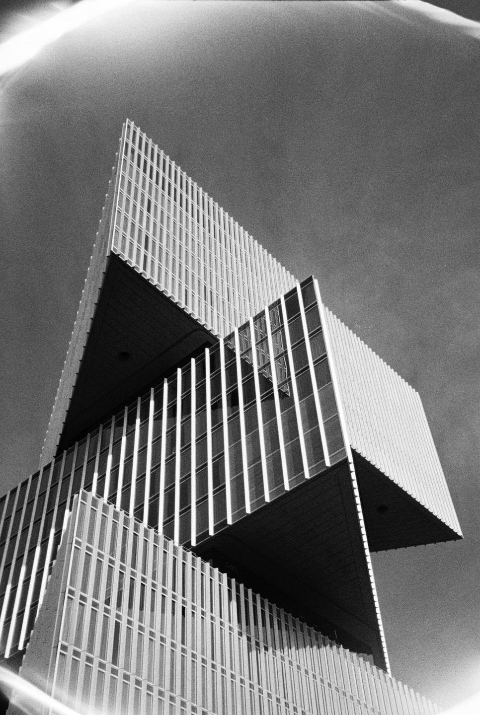 A low-angle view shows the geometric facade of a modern building against a clear sky.