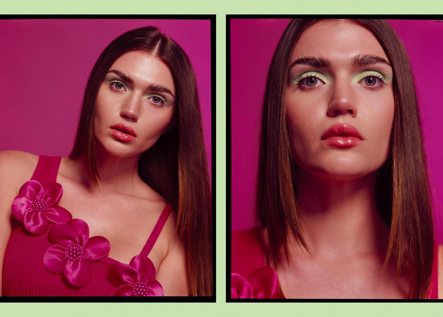 A woman with long hair and bright green eyeshadow poses for a portrait against a magenta background.