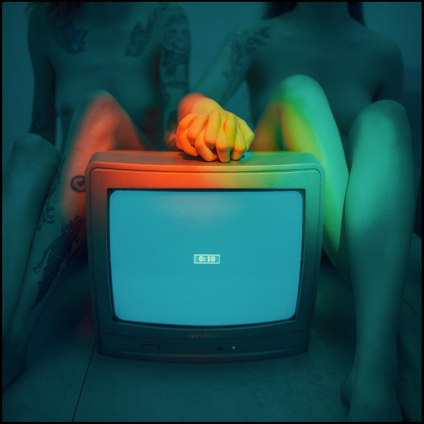 Two people sit behind a television displaying "0:10" on its screen.