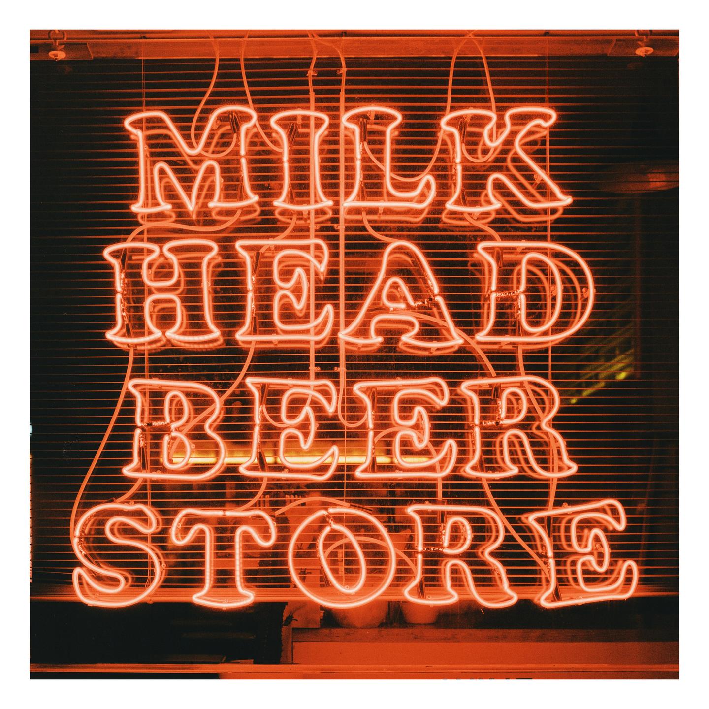 An orange neon sign for "Milk Head Beer Store" is displayed in a window.