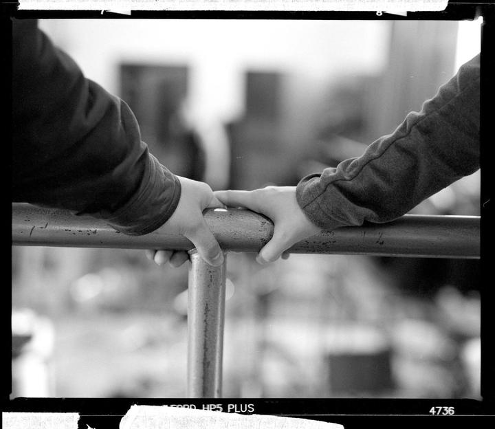 Two people hold onto a metal railing.