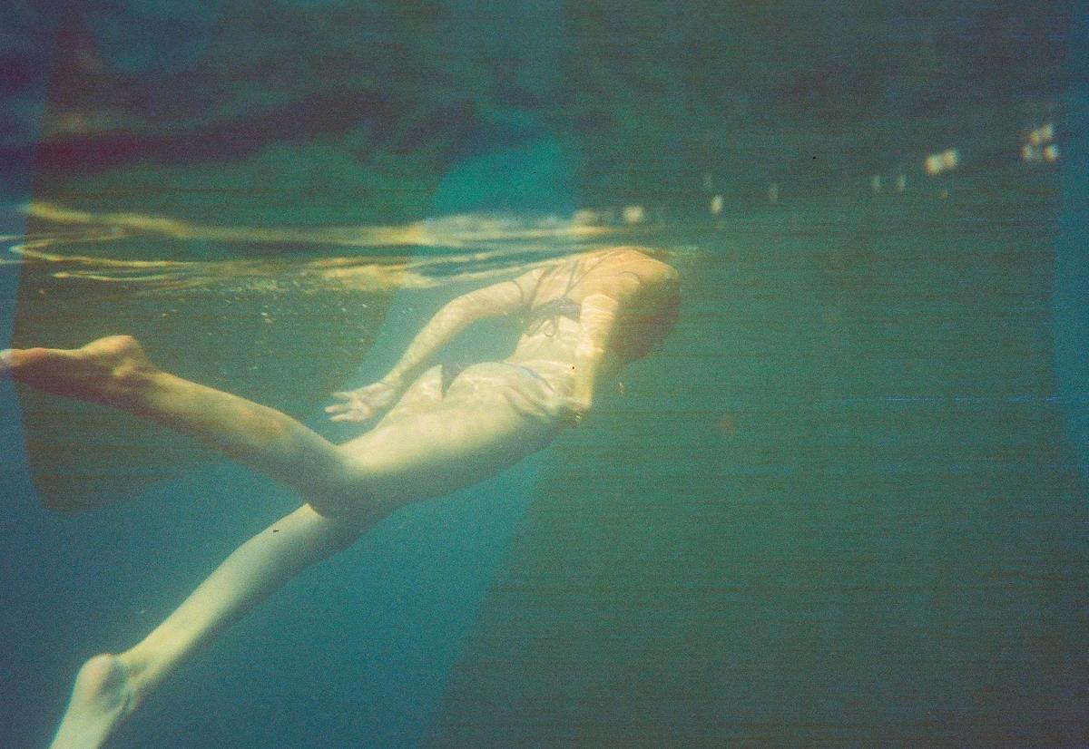 A woman swims underwater with her head partially submerged.