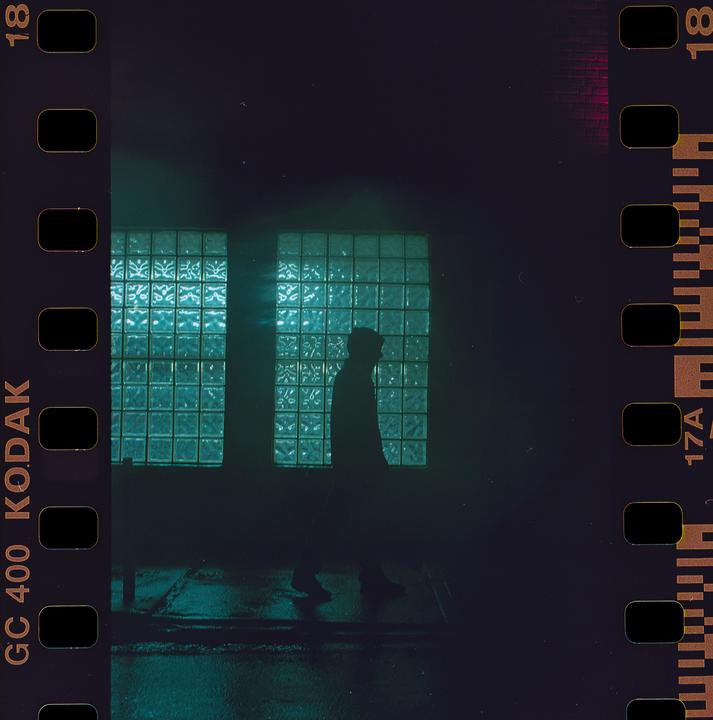 A man walks past two large windows made of glass blocks at night.
