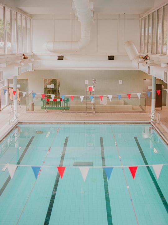 A swimming pool with red, white, and blue bunting strung across it is empty.