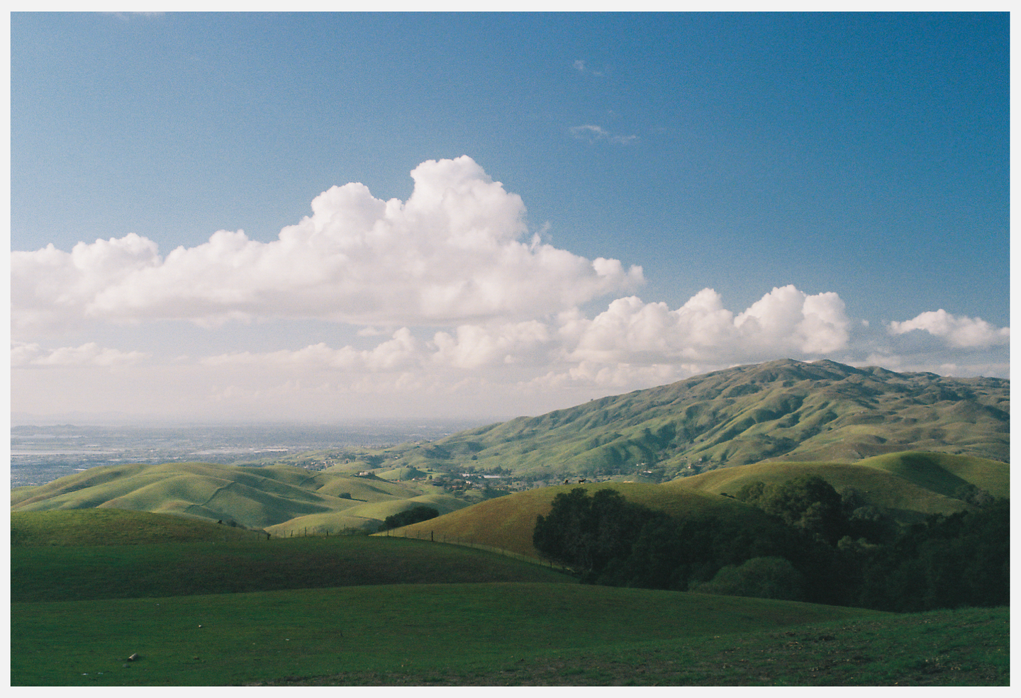 Rolling green hills are visible under a blue sky with white clouds.