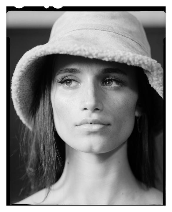 A woman wearing a bucket hat looks up and to the right.