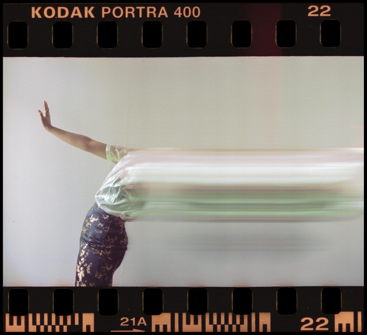 A person with a blurred torso and arm raised stands against a light background.