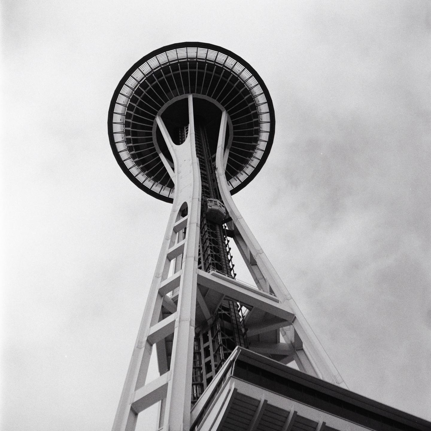 The Space Needle in Seattle is viewed from below against a cloudy sky.