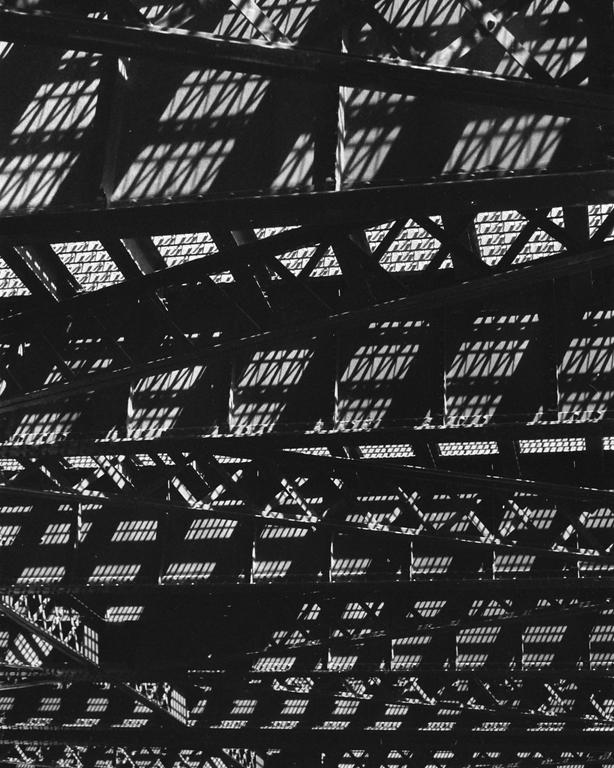 Sunlight casts geometric shadows through a metal structure.