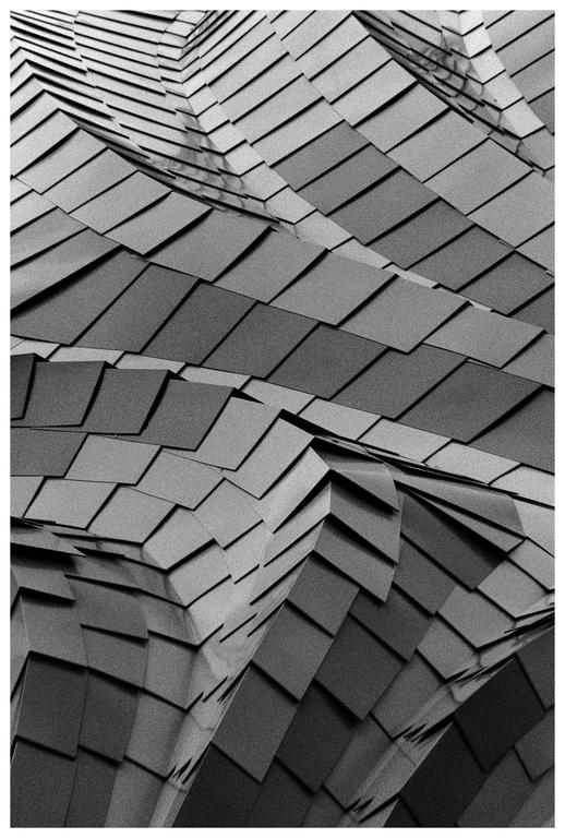 A close-up, abstract view of a building facade shows a pattern of rectangular panels.