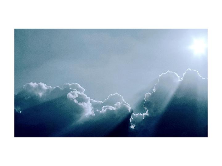 Sunlight streams through clouds in a bright sky.