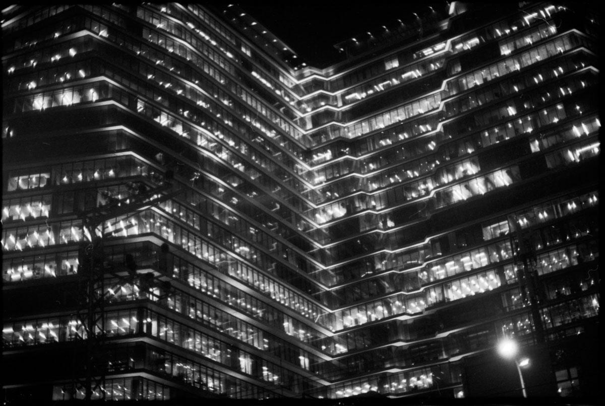 A large building with many illuminated windows is photographed at night.