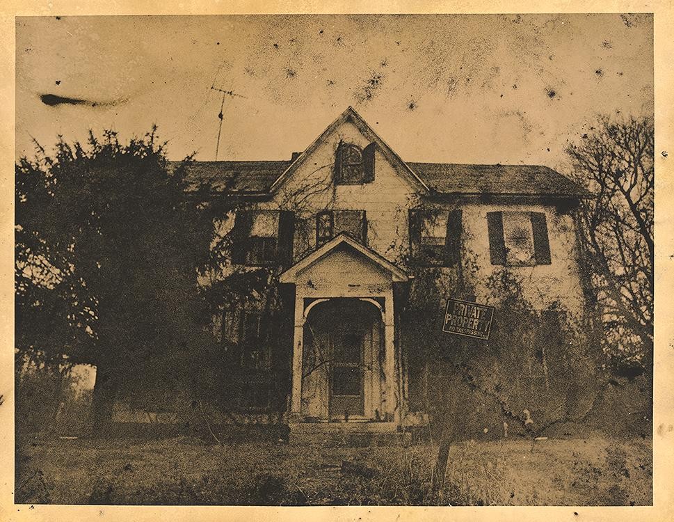An old, dilapidated house with a "Private Property" sign on the front is surrounded by overgrown trees and grass.