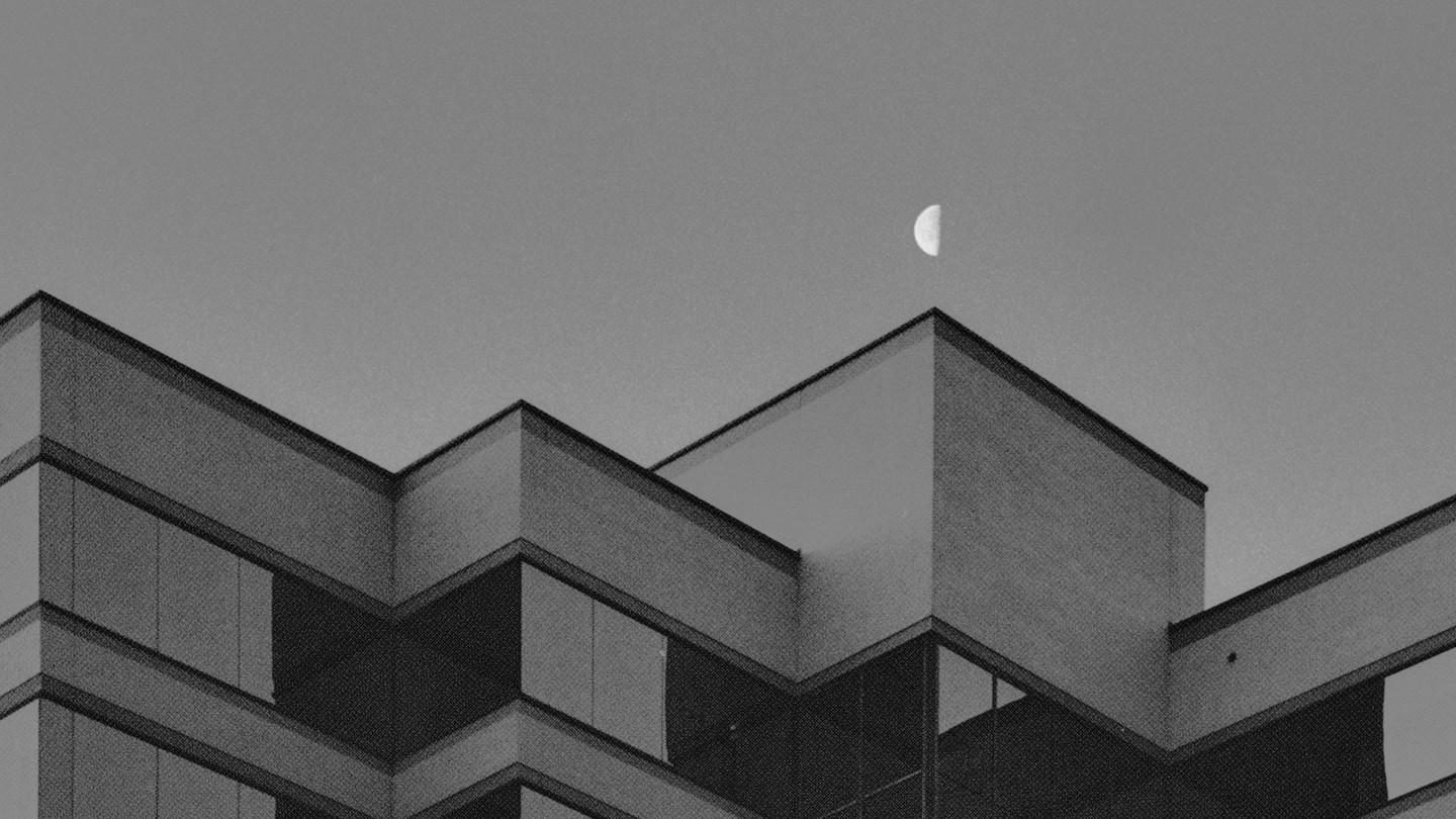 A half moon is visible above the angular roofline of a building.