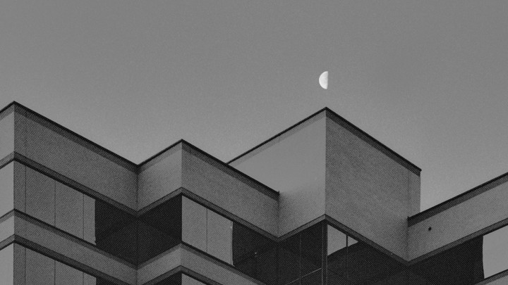 A half moon is visible above the angular roofline of a building.