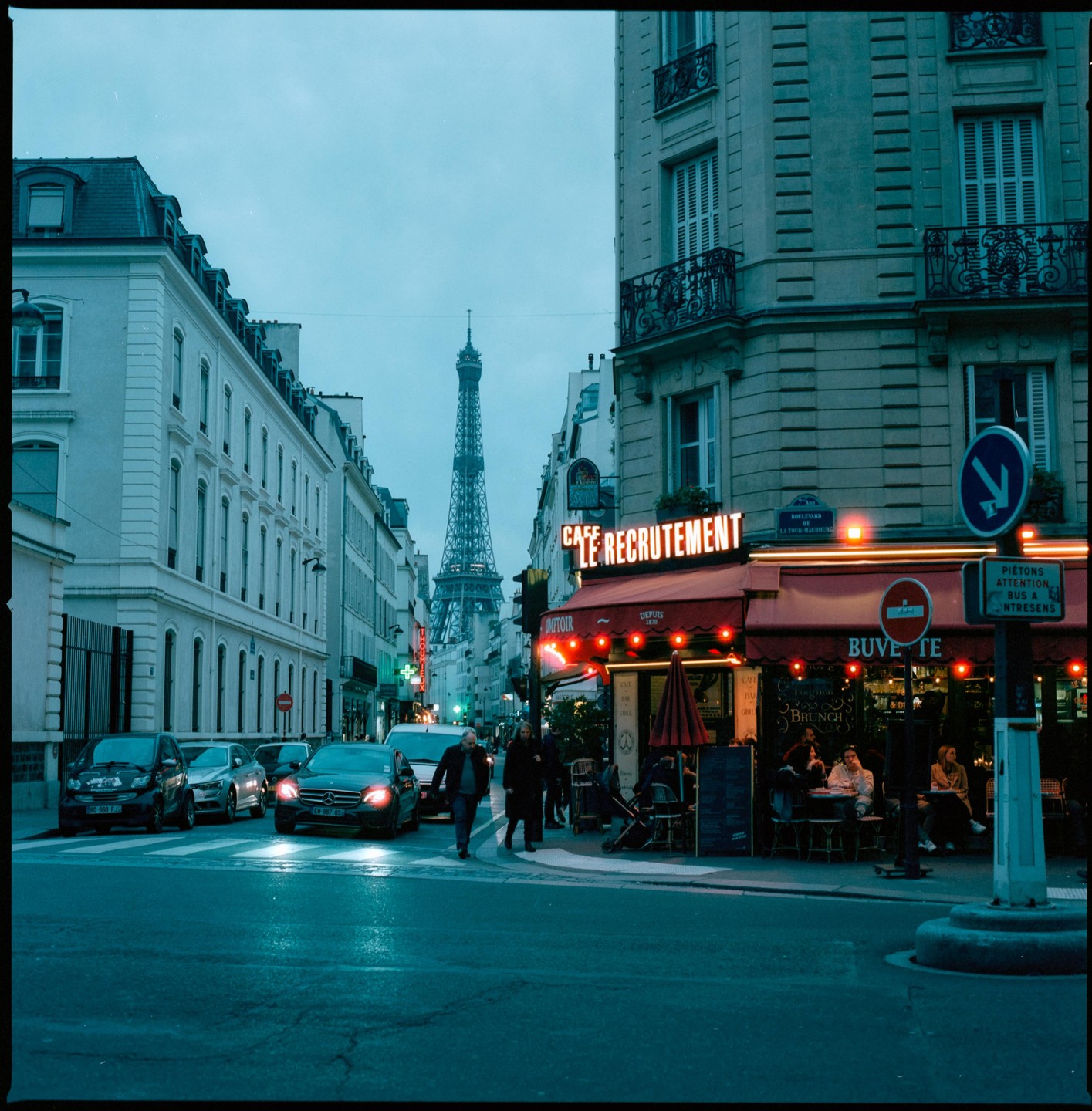 A street in Paris with the Eiffel Tower in the background and a cafe with outdoor seating in the foreground.