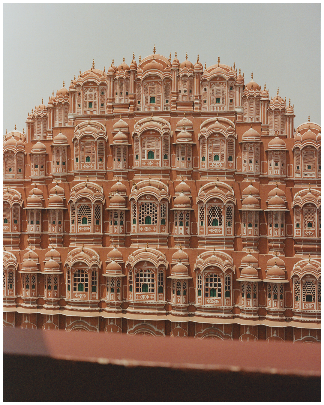 The Palace of the Winds in Jaipur is a large, ornate building with many windows and domes.