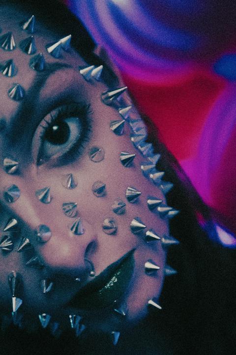 A person's face is covered in spikes, with one eye and part of the mouth visible.