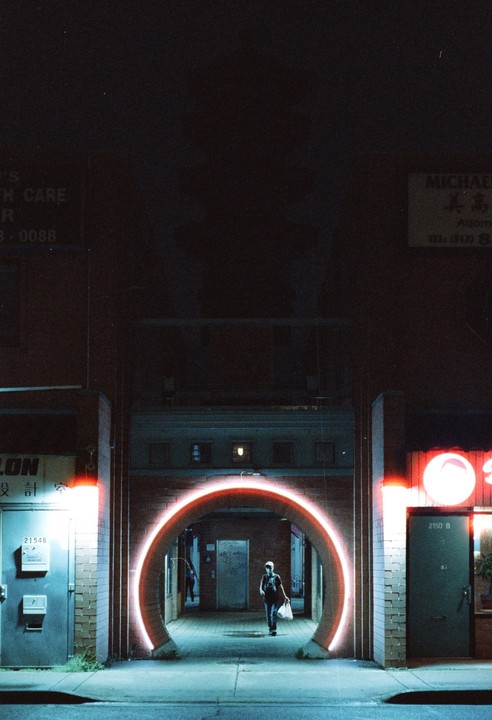 A person walks through a glowing red circular archway at night.