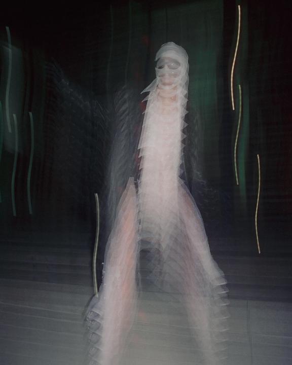 A person with a bandaged head and face is captured in a blurry, streaked long exposure.