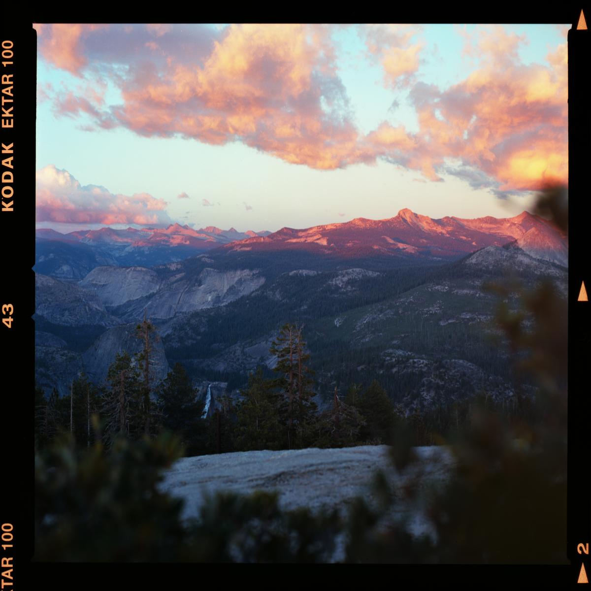 A mountain landscape is visible under a sky with pink clouds at sunset.