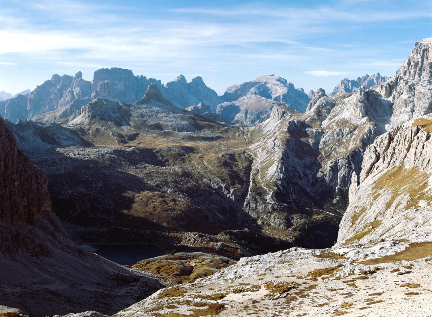 A vast mountain landscape with a small lake visible in the valley.