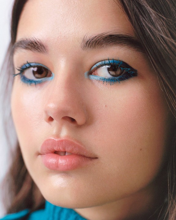 A woman with blue eyeliner and mascara looks directly at the viewer.