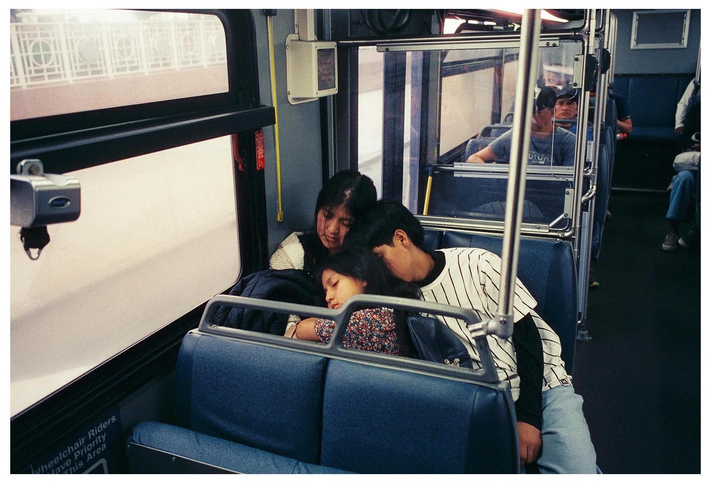 A woman, man, and child are sleeping on a bus.