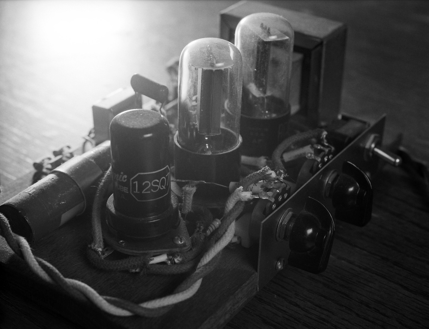 A close-up view shows the internal components of an electronic device, including vacuum tubes and wiring.
